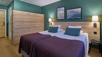 A hotel room with two beds, a wardrobe, and artwork on the walls.