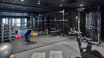 A gym with weightlifting equipment, kettlebells, and exercise machines.