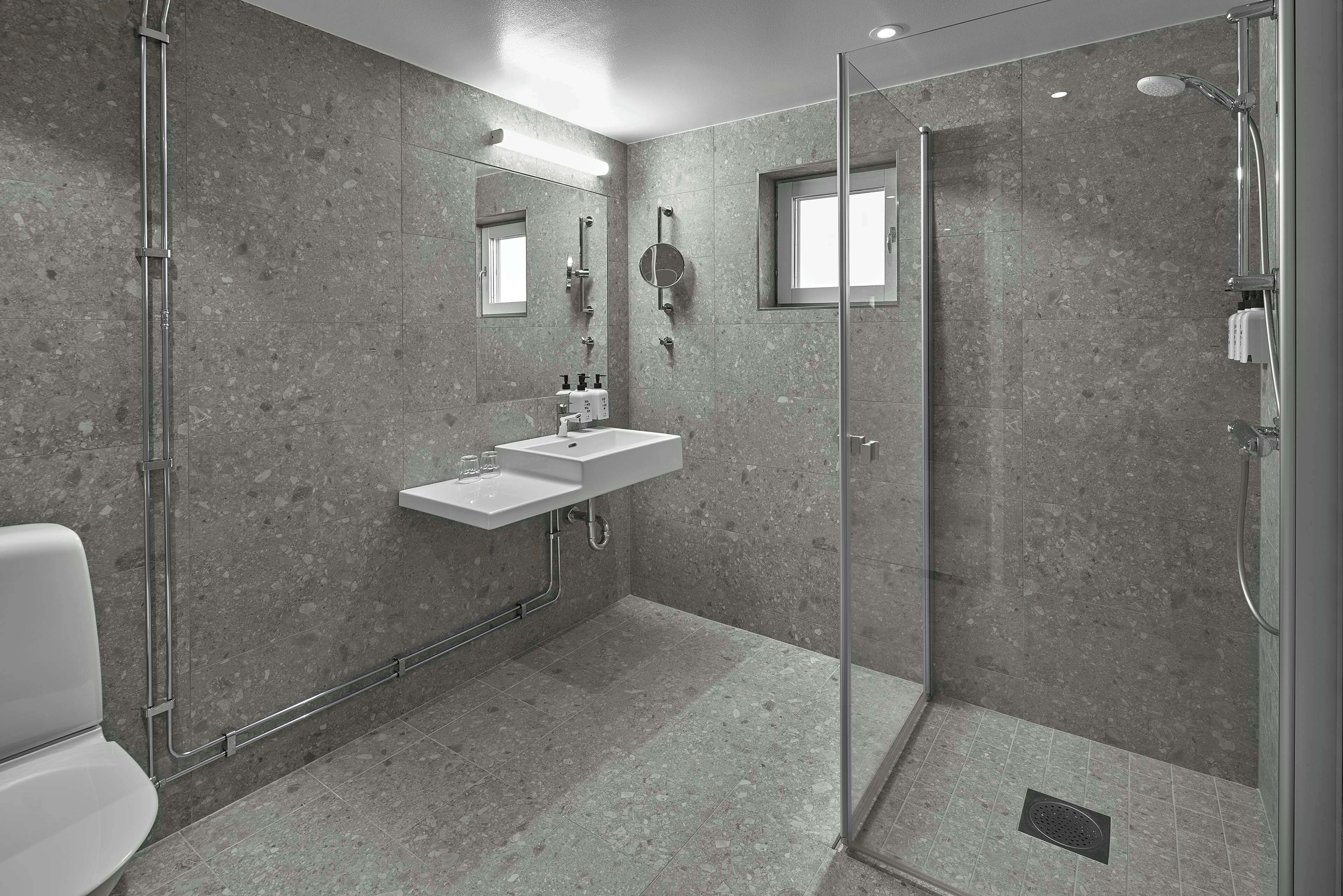 Een moderne badkamer met een douchecabine van glas, een wit wastafelmeubel en een spiegel.