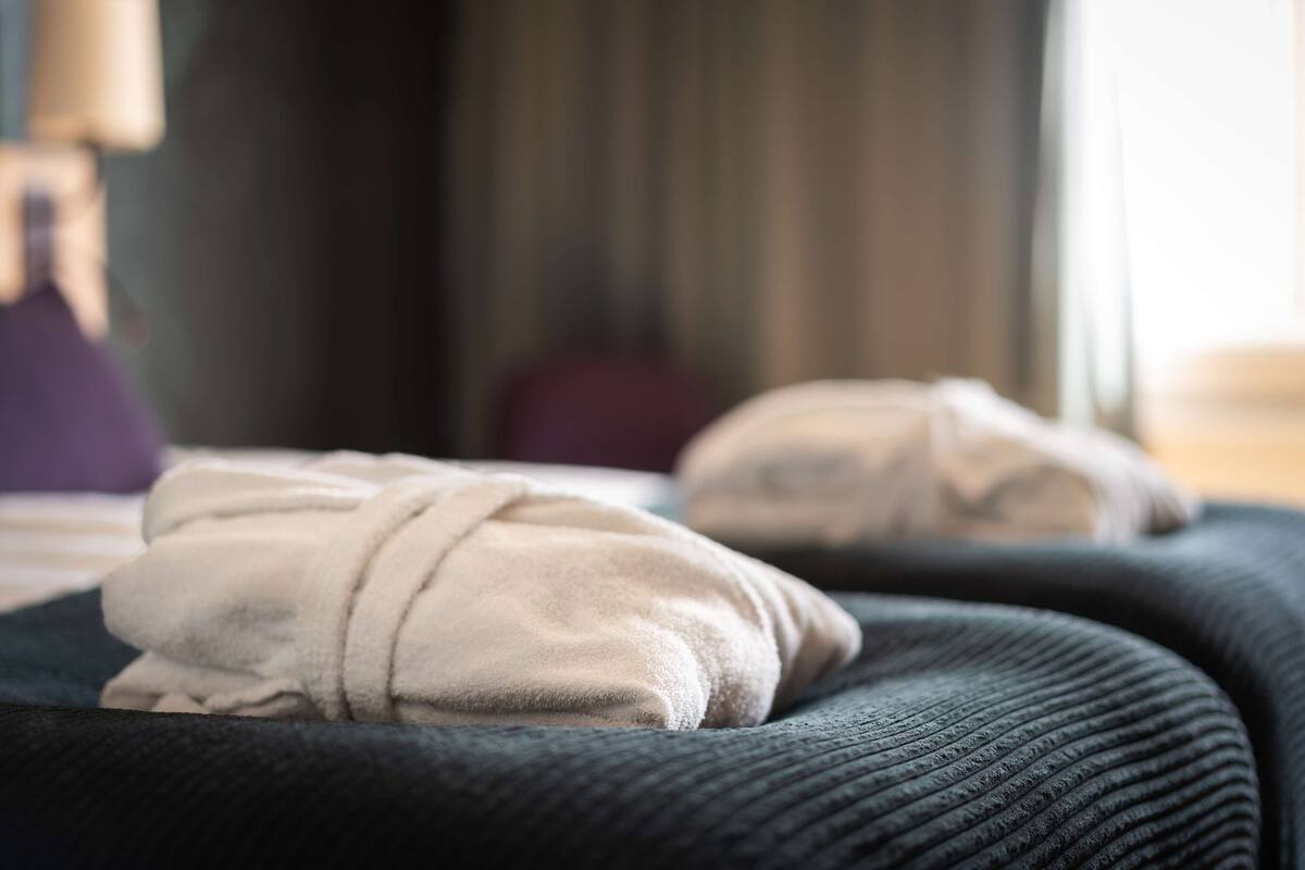 A bed with a dark cover and two pillows.