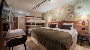 Een hotelkamer met een bed, een bureau, een stoel, een televisie en een wand met een bloemmotief.