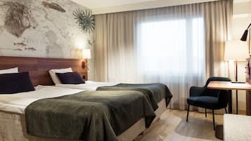 Habitación de hotel con dos camas, un mapa en la pared, un escritorio y una silla.