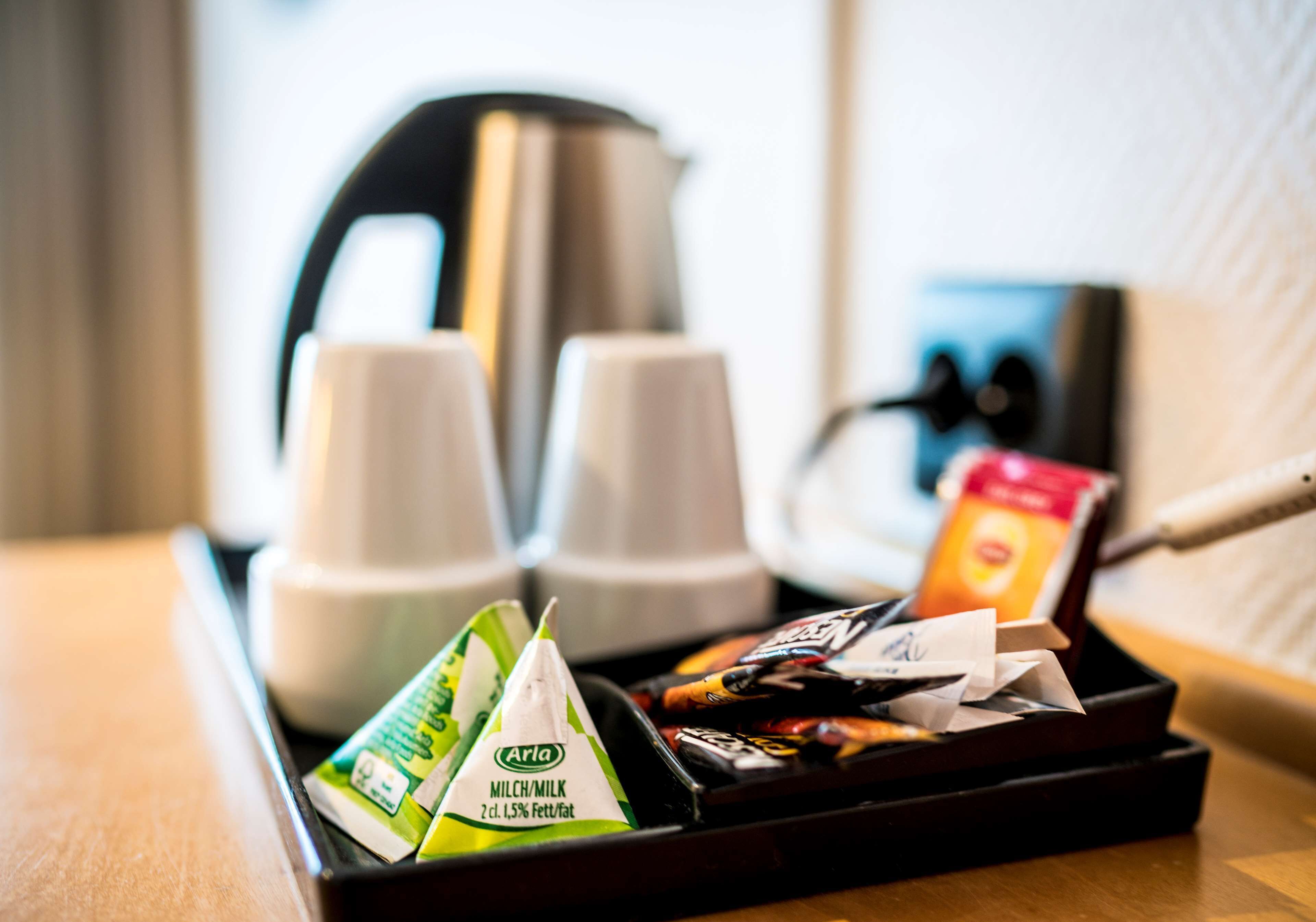 A tray with coffee cups, a kettle, and packaged snacks.