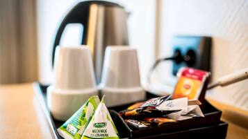 A tray with coffee cups, a kettle, and packaged snacks.