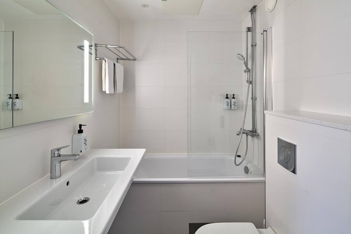 A modern bathroom with a white sink, mirror, and shower.