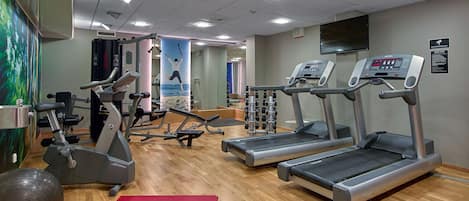 Un gimnasio con cintas de correr, pelotas de ejercicio y máquinas de pesas.