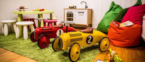 A playroom with a toy train, stools, a small table, and a bean bag.