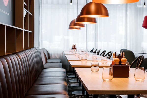 Un restaurante moderno con asientos de cuero, mesas de madera e iluminación colgante de cobre.