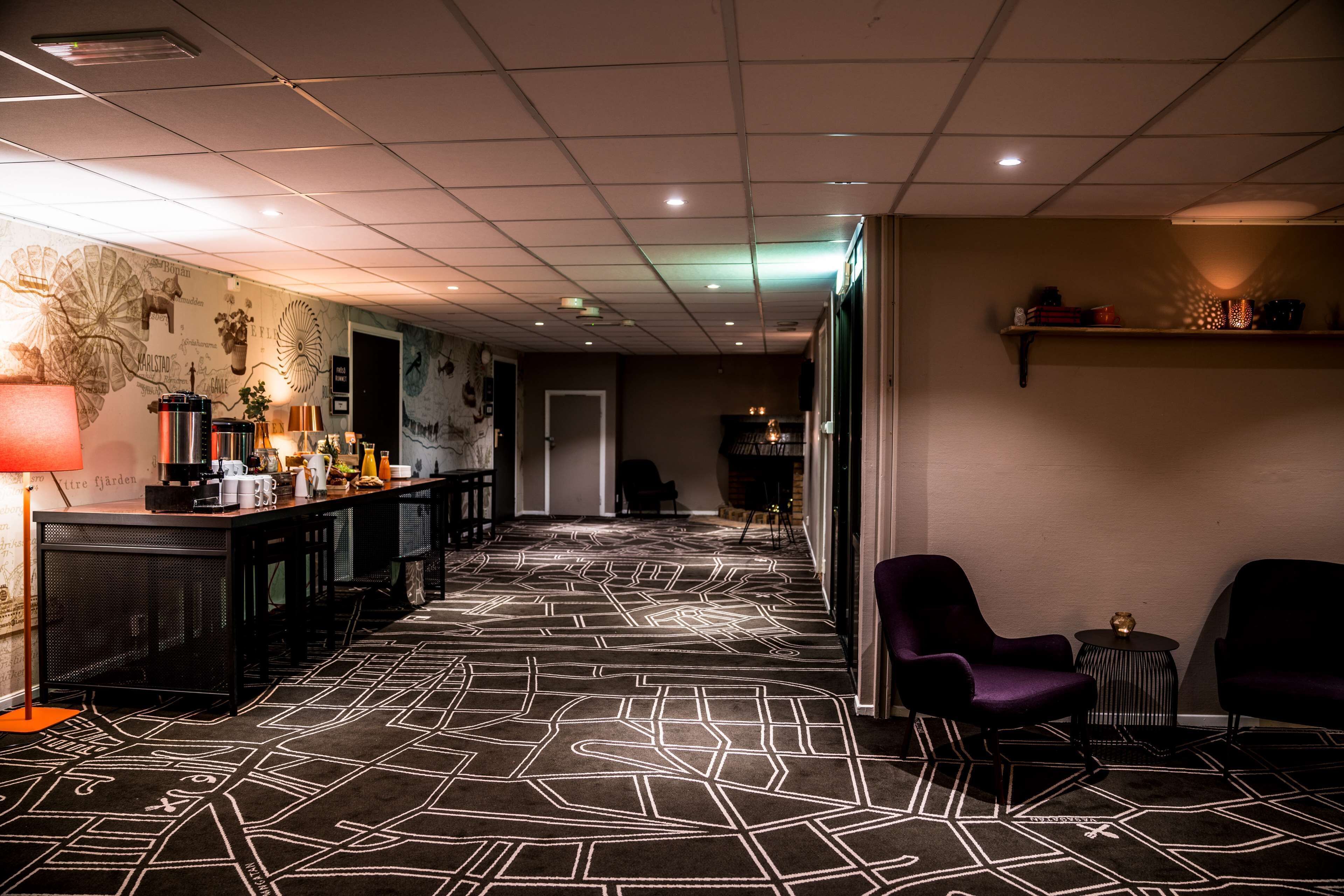 A hotel lobby with a patterned carpet, a reception desk, and seating areas.
