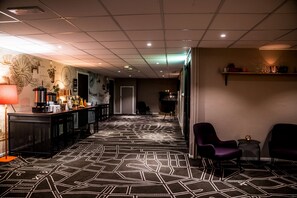 Vestíbulo de hotel con alfombra estampada, una recepción y zonas de estar.
