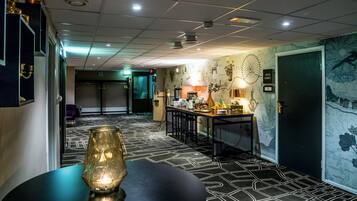 Un vestíbulo de hotel con diseño moderno, que incluye una zona de bar, asientos y una pared decorativa.