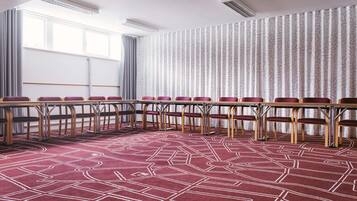 A conference room with a long table, chairs, and a patterned carpet.