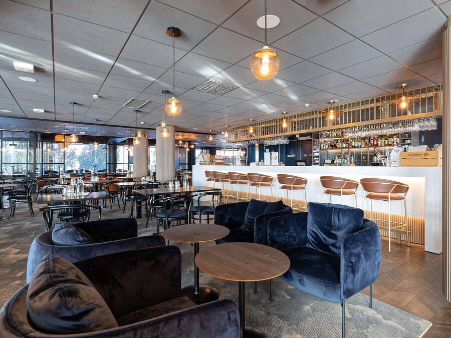 Un área de bar moderna con mostrador, asientos y vistas al exterior.