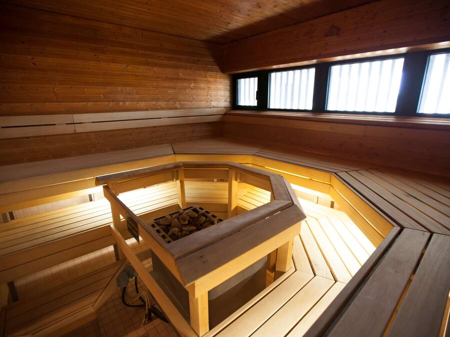 A wooden sauna with benches and a central heating area.
