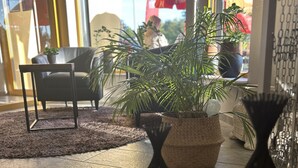 Ein modernes Interieur mit einem Blumentopf, einem schwarzen Metalltisch und einer Sitzecke mit einer Couch und einem Couchtisch.