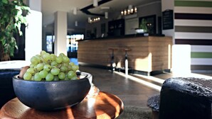 Eine Schüssel mit grünen Trauben auf einem Holztisch in einer modernen Lobby mit einer Rezeption und einer Treppe.