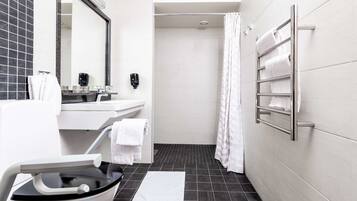 A modern bathroom with a white sink, a mirror, a shower with a curtain, and a towel rack.
