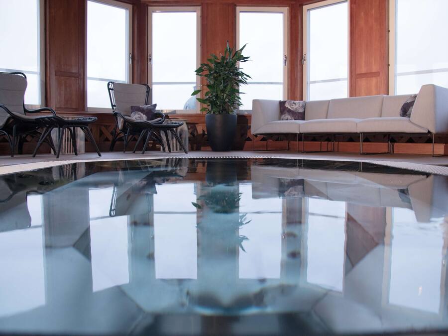 A pool area with a glass floor, wooden walls, and a sofa.