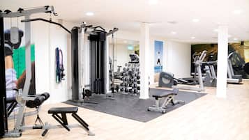 Un gimnasio con equipo de ejercicio variado, incluyendo máquinas de pesas, cintas de correr y una banca.