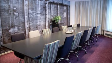 A conference room with a long table, striped chairs, a potted plant, and a wooden accent wall.