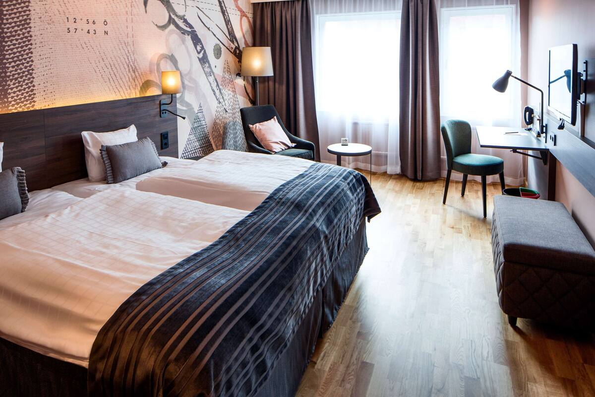 A hotel room with a large bed, two chairs, a desk, and a small table.