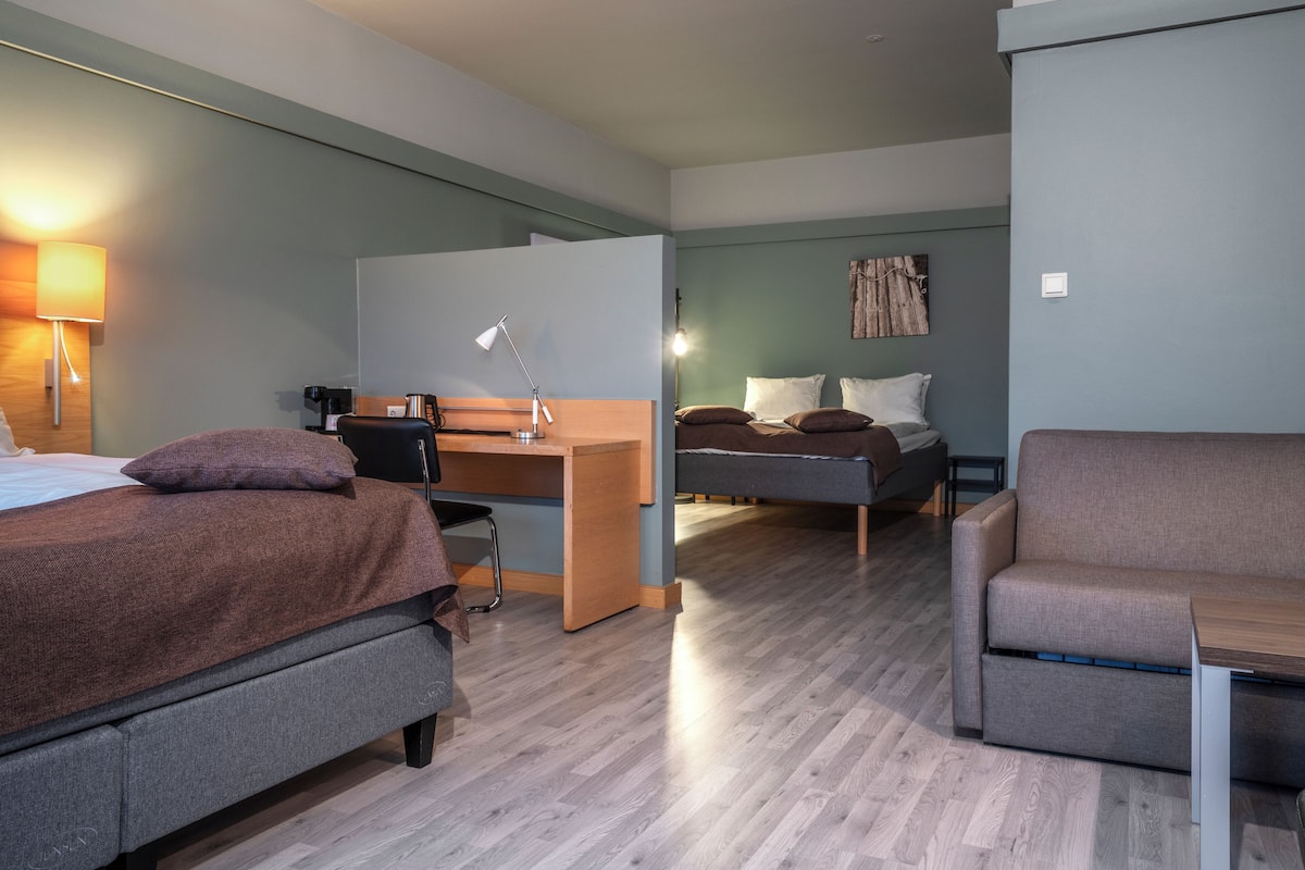 Quarto de hotel moderno com cama, escrivaninha e área de estar.