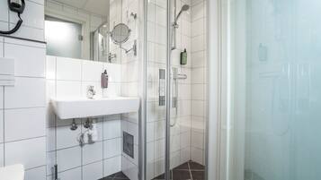 A modern bathroom with a glass shower enclosure, a white sink, and a mirror above it.