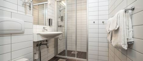 Un baño moderno con inodoro, lavamanos y ducha con mampara de vidrio.