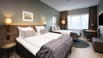 A hotel room with two beds, a desk, a chair, and a TV.