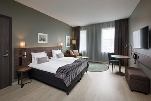 Une chambre d’hôtel avec un grand lit, une petite table, une chaise, un canapé et un téléviseur.