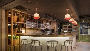 A bar area with a wooden counter, bar stools, and hanging pendant lights. - Scandic Sjølyst (Oslo)