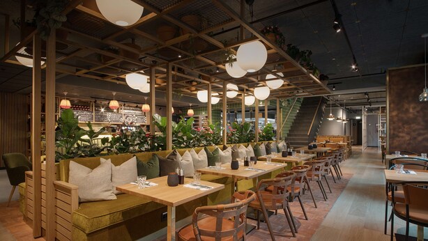 A modern restaurant with wooden furniture, green cushions, and hanging pendant lights. - Scandic Sjølyst (Oslo)