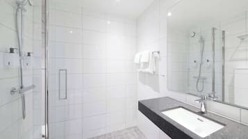 A modern bathroom with a glass-enclosed shower, a black countertop sink, and a large mirror.