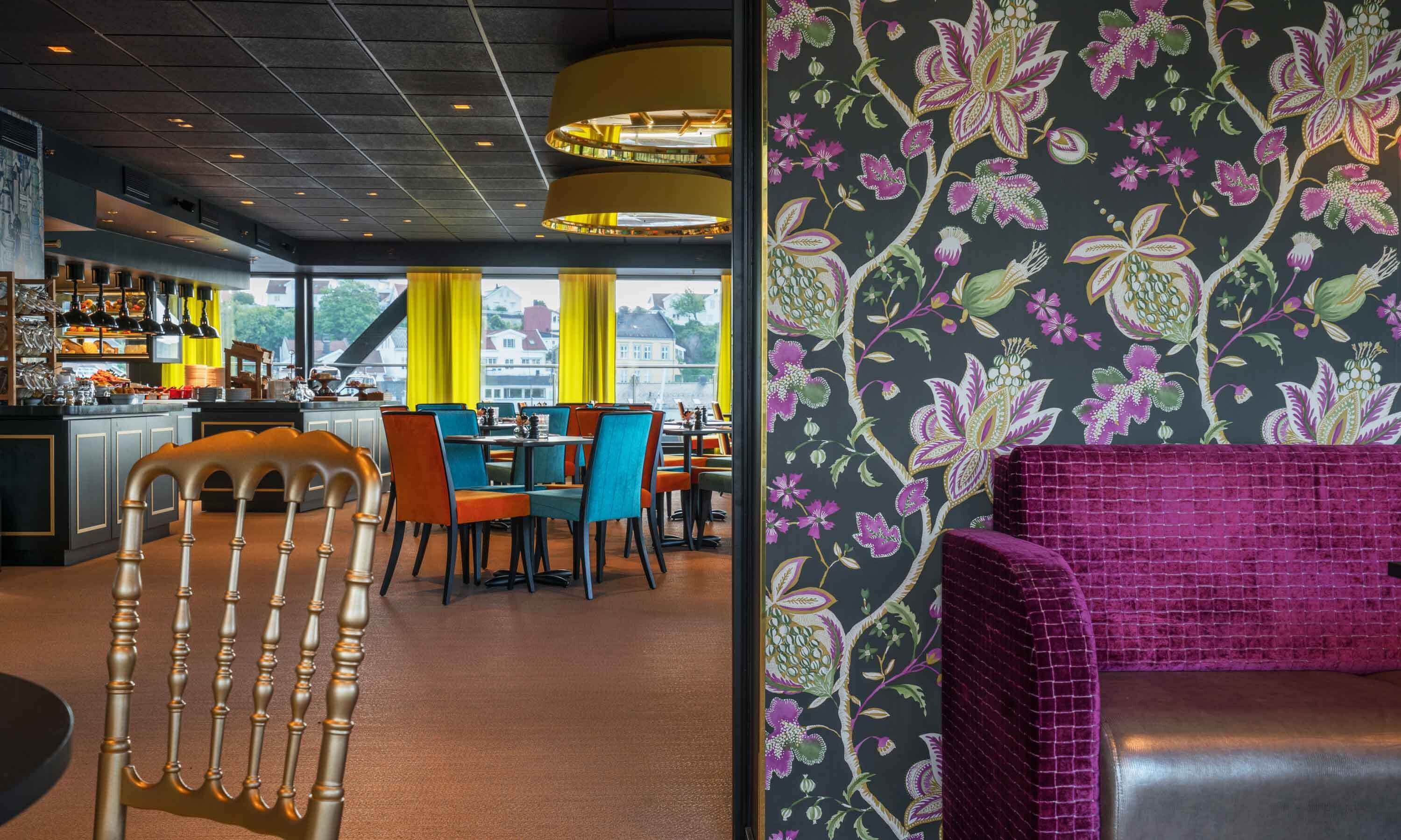 A restaurant with a bar area, colorful chairs, and a purple cushioned seating area.
