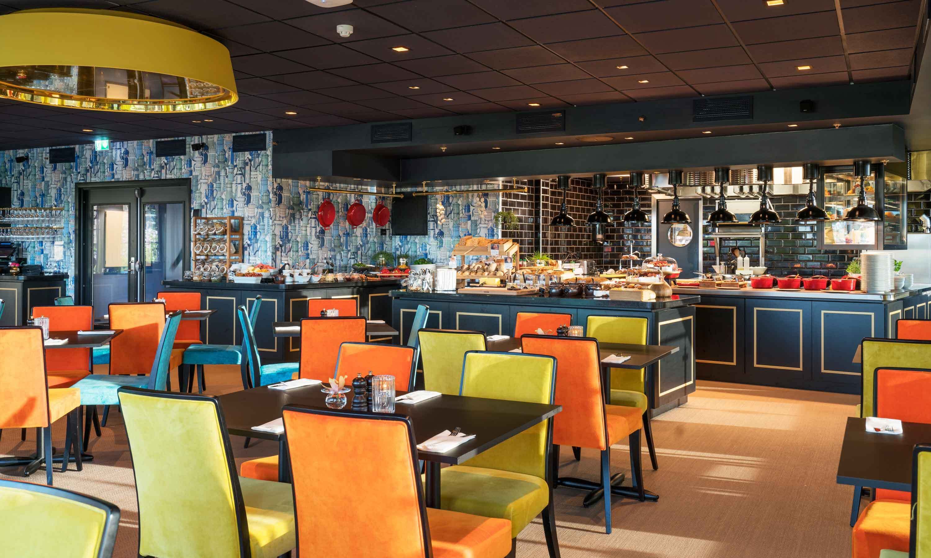 Un restaurante con barra central, sillas coloridas y una zona de bufé.