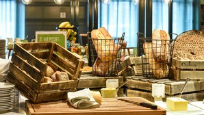 A bakery display with various breads and pastries, wooden crates, and a sign indicating 'At Hur Mycket'. - Scandic Crown (Gothenburg)