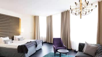 Ett hotellrum med en stor säng, en stol, en soffa och en kristallkrona.