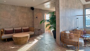 A spacious lobby with a modern design, featuring a sofa set, wicker chairs, and a large potted plant. - Scandic Crown (Gothenburg)