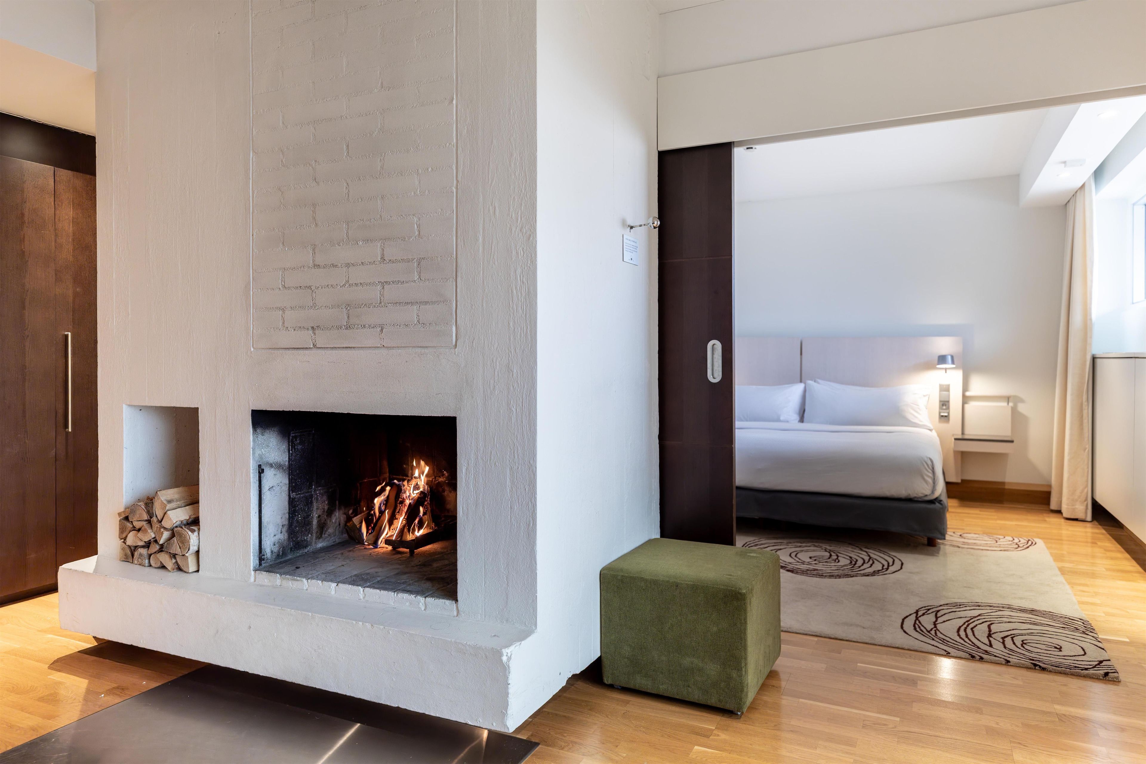 Un dormitorio moderno con chimenea, una cama y una mesita de noche.