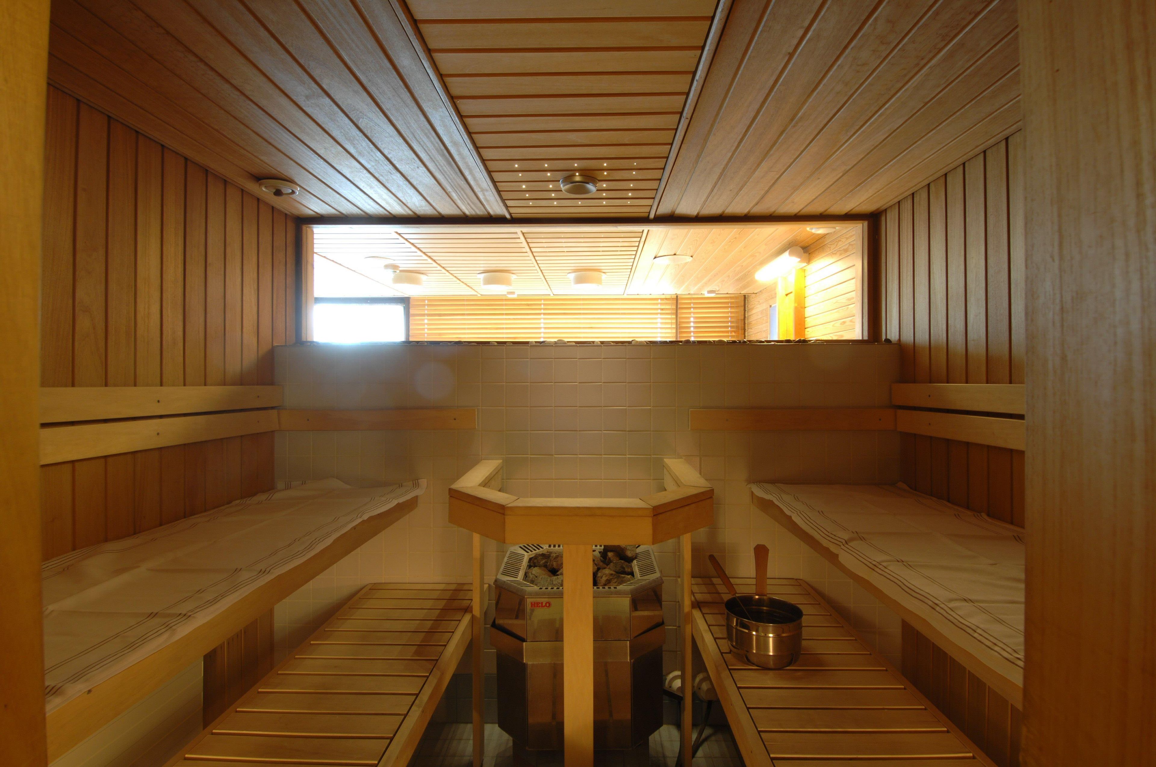 Uma sauna com bancos de madeira, uma mesa central e um fogão.