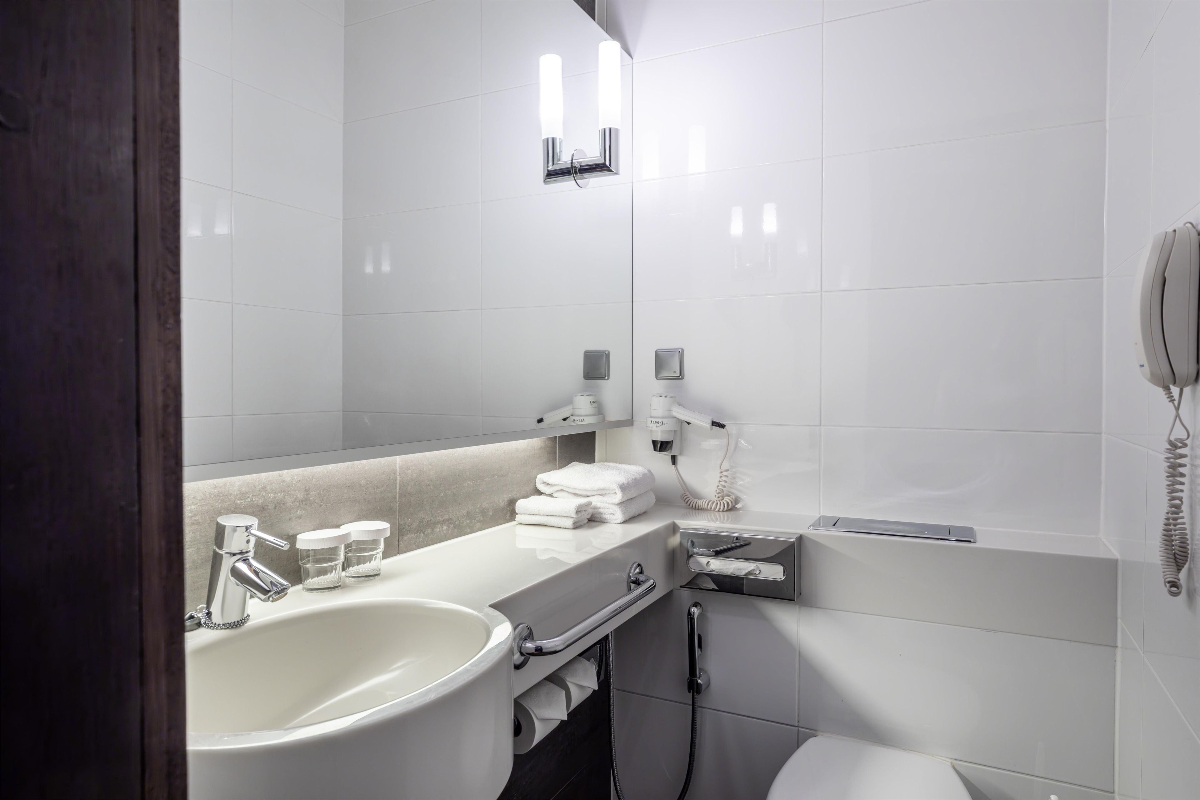 Un baño moderno con un lavamanos grande, un espejo, un secador de pelo y un teléfono.