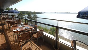 A terrace with tables and chairs, overlooking a body of water. - Hilton Helsinki Kalastajatorppa (Helsinki)