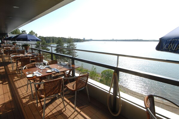 A terrace with tables and chairs, overlooking a body of water. - Hilton Helsinki Kalastajatorppa (Helsinki)