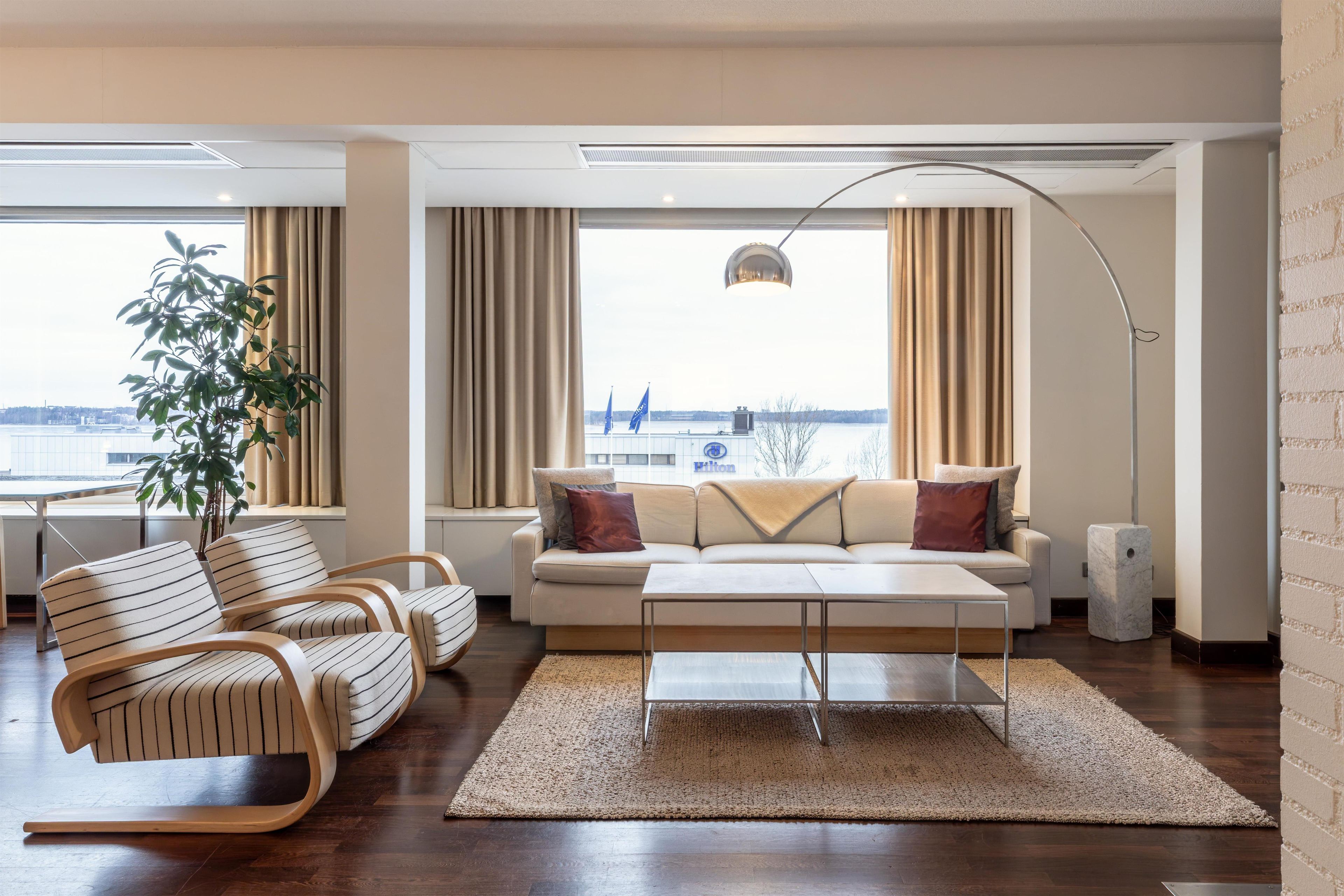 A modern living room with a sofa, chairs, a coffee table, and a view of a body of water.