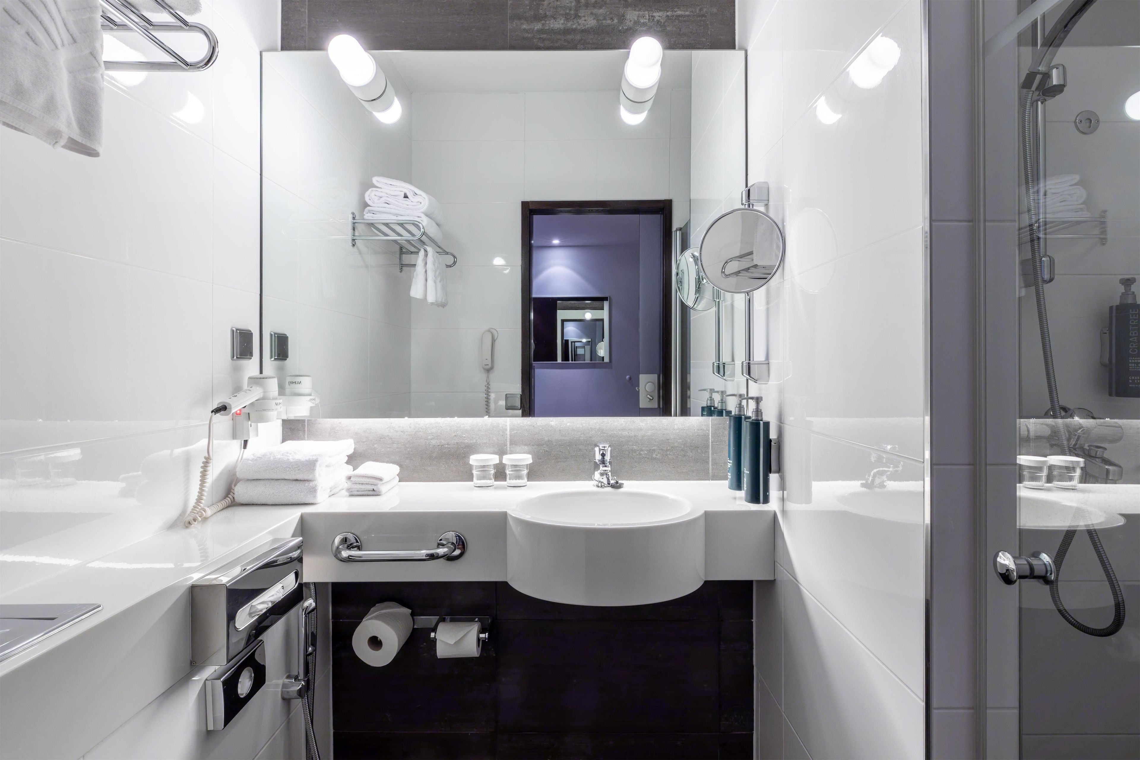 Un baño moderno con dos lavamanos, un espejo y una ducha.