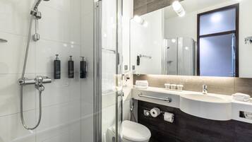 A modern bathroom with a glass-enclosed shower, a toilet, a sink with a vanity, and a mirror above the sink.