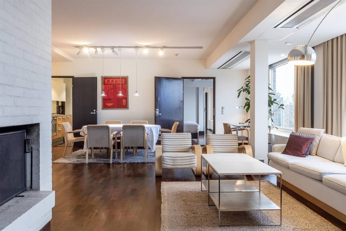 Ein modernes Wohnzimmer mit Kamin, Essbereich und einer Couch.