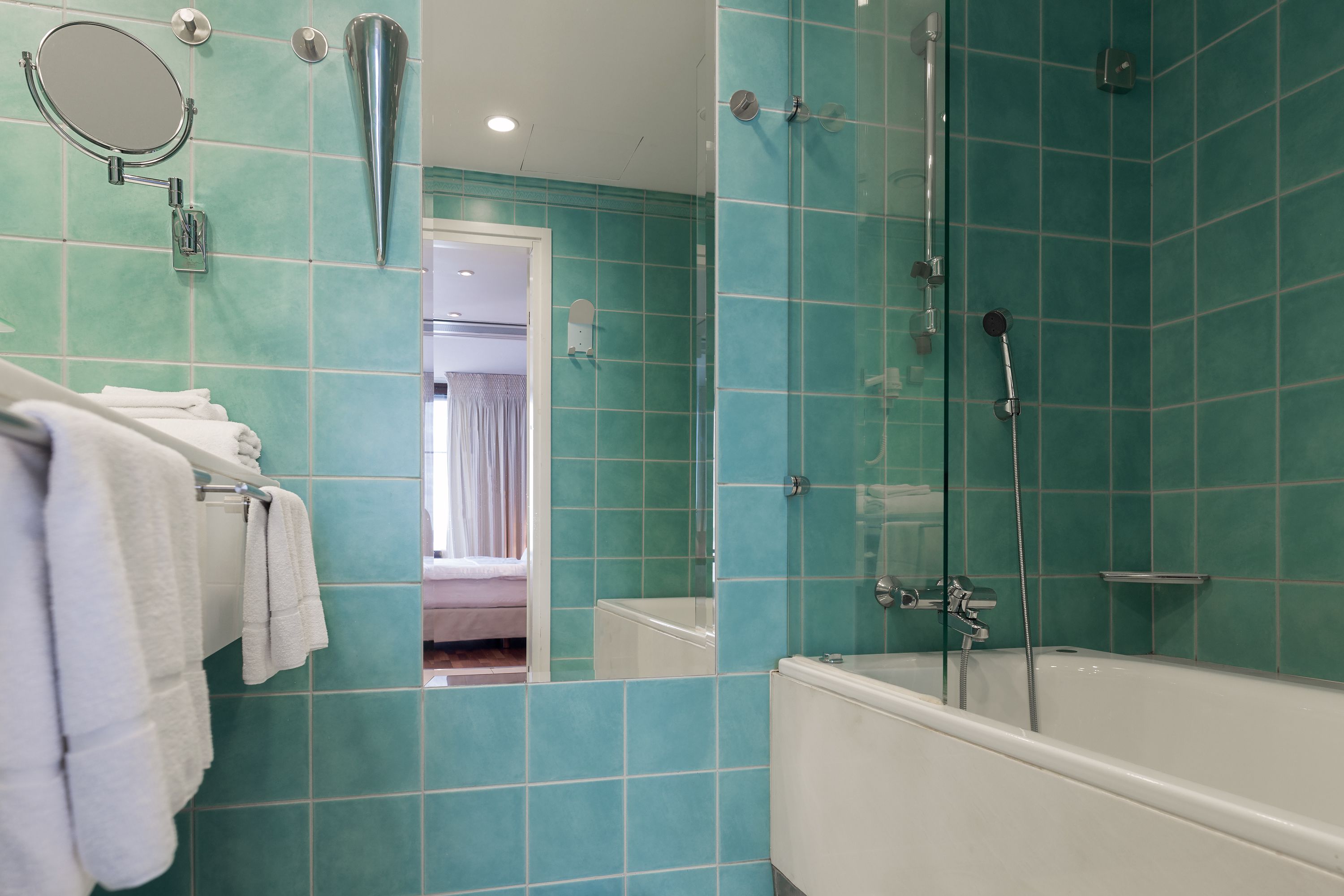 Un bagno con piastrelle color turchese, una vasca, una doccia e uno specchio.