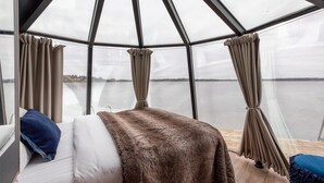 A room with a bed, a view of a lake, and a glass ceiling. - Hilton Helsinki Kalastajatorppa (Helsinki)