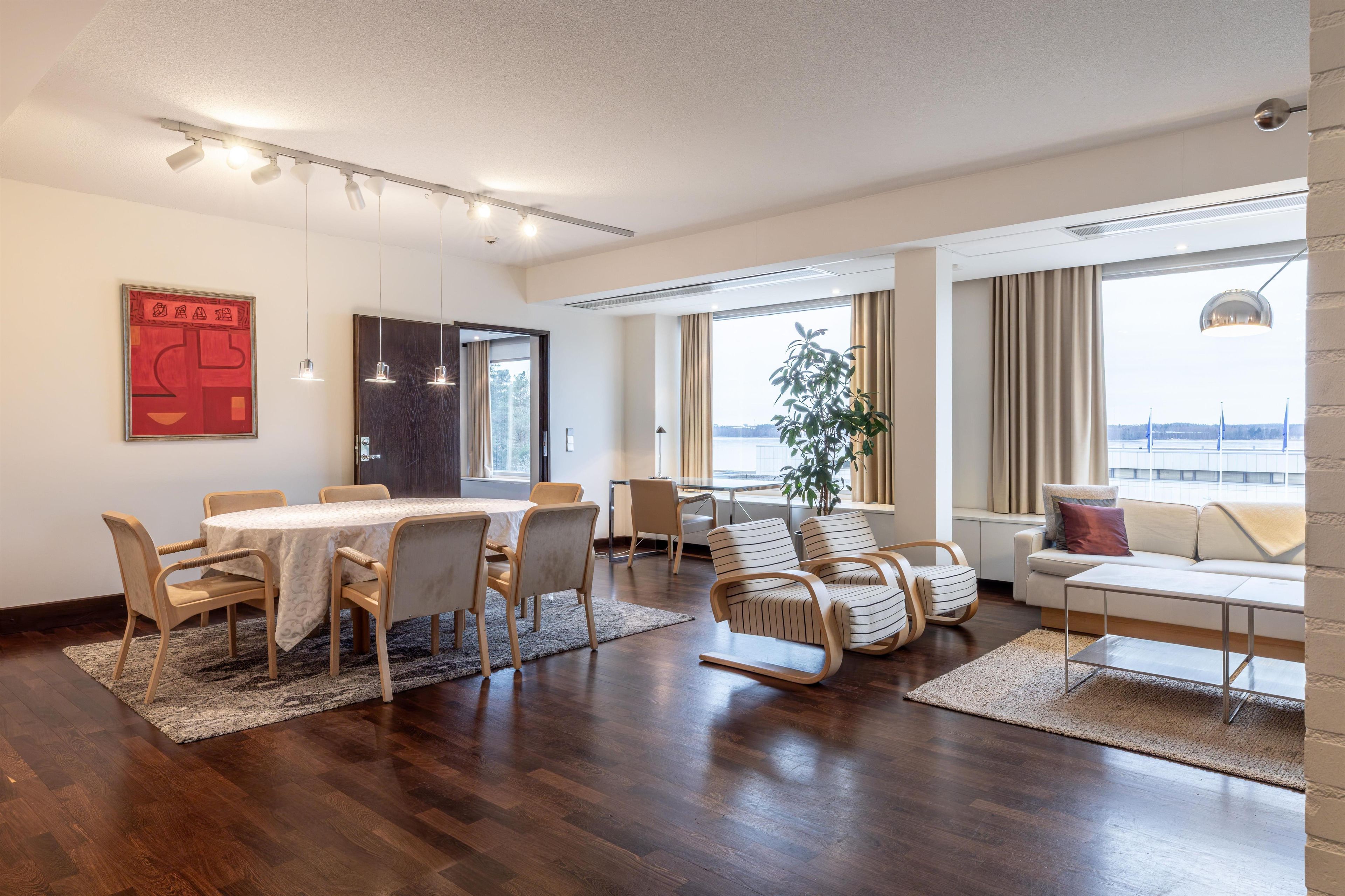 A modern living room with a dining area, large windows, and a view of the water.